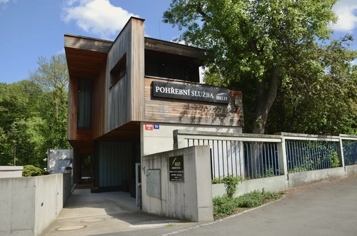 Sídlo Pohřební služby HELFI v Praze 4 – Krči, moderní budova s dřevěným obkladem, nápis na fasádě a informační tabule u vjezdu
