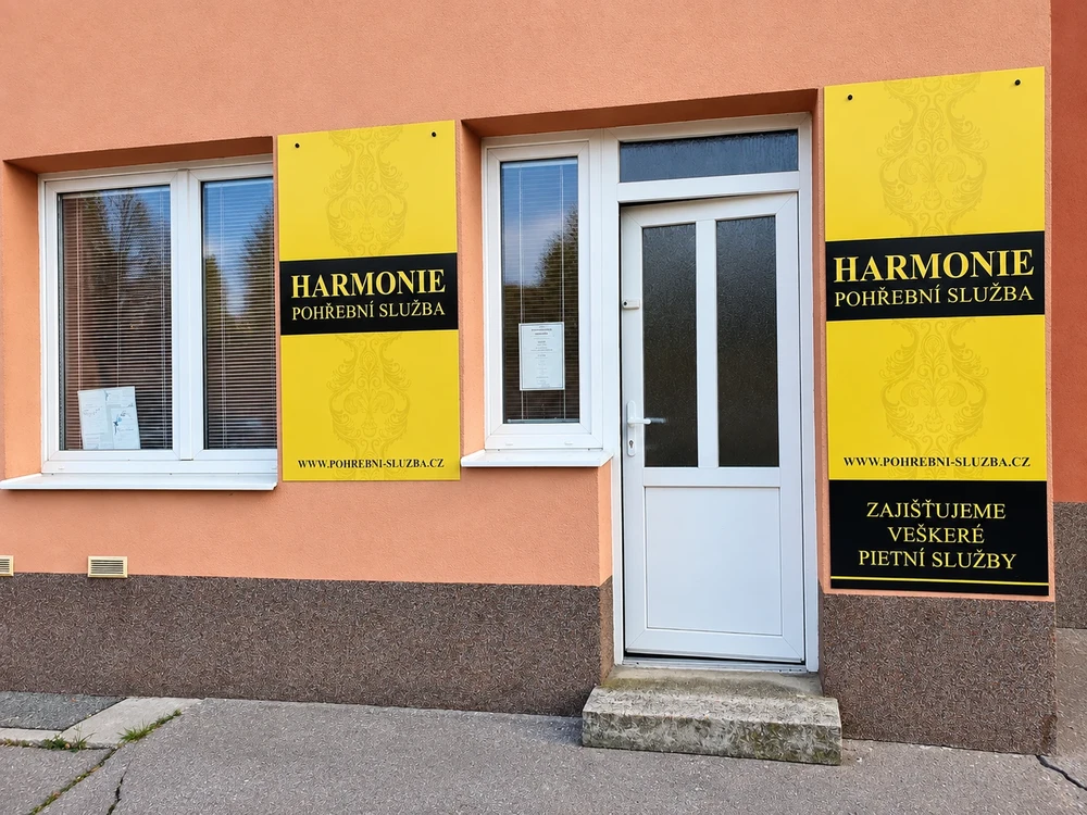 Provozovna Pohřební služby Harmonie na Mikuláškově náměstí 1 v Brně se žlutými cedulemi na oranžové fasádě a bílými vstupními dveřmi.
