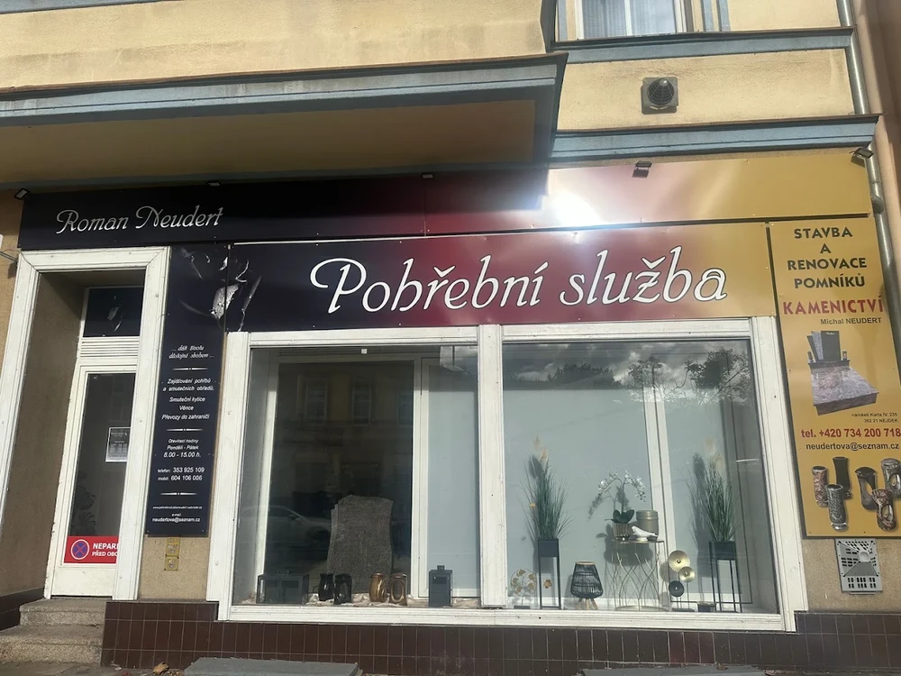 Provozovna pohřební služby Roman Neudert s výlohou s urnami a lucernami, vedle reklama na kamenictví.